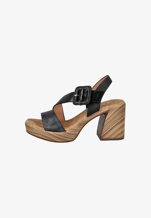 Sandalia de cuero negro con correas anchas, hebilla tejida, plantilla acolchada color beige y tacón grueso con textura de veta de madera.