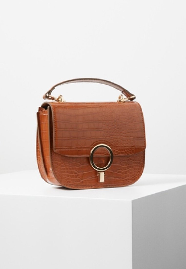 Brązowa torebka z lakierowanej skóry ekologicznej imitującej krokodyla, z złotym okrągłym zapięciem, o solidnej konstrukcji i odpinanym paskiem na ramię.