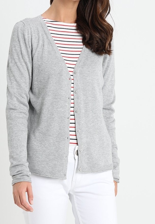 Cárdigan gris de punto con cuello en V y botones frontales, llevado sobre una camiseta de rayas rojas y blancas, combinado con pantalones blancos. Textura suave.