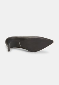 Scarpa nera con tacco alto e design a punta, in pelle liscia e con tacco stiletto sottile. La parte inferiore presenta un motivo testurizzato per una migliore aderenza.