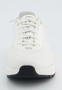 Weißer Sportschuh mit einem strukturierten Textiloberteil, einem grauen gepolsterten Kragen und einer schwarzen Gummisohle. Verfügt über Schnürsenkel und durchbrochene Details.