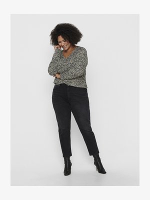 Blusa de mangas longas preta com um padrão floral, combinada com calças de ganga pretas de cintura alta e botins pretos. A modelo está em uma pose relaxada.