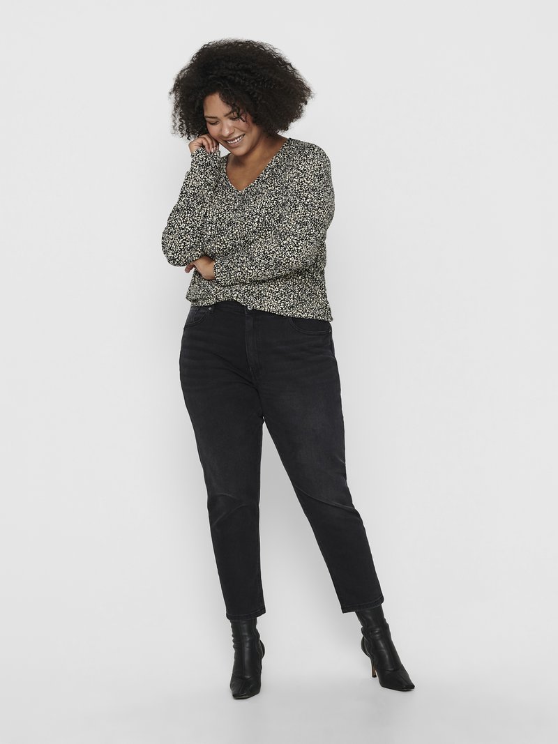 Blusa de mangas longas preta com um padrão floral, combinada com calças de ganga pretas de cintura alta e botins pretos. A modelo está em uma pose relaxada.