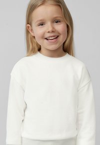 Biała, długosleeve'owa bluza z okrągłym dekoltem, charakteryzująca się luźnym krojem i miękką teksturą. Minimalistyczny design bez widocznych wzorów lub akcentów.