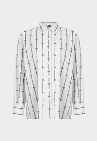 Chemise blanche boutonnée avec lignes verticales noires et motifs géométriques, coupe ajustée, manches longues avec détails de poignets contrastants.