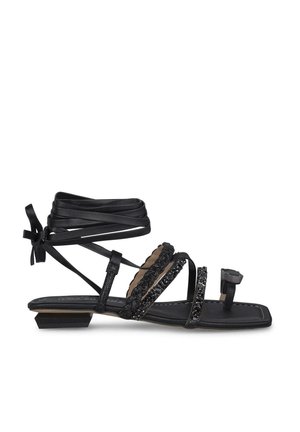 Black sandal with multiple straps, beaded accents, and a flat heel. Designed with ankle ties and a decorative buckle. Textured sole.