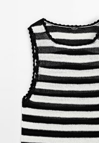 Haut sans manches tricoté à rayures horizontales noires et blanches, avec bords festonnés et encolure arrondie.