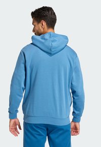 Felpa blu con cappuccio dalla finitura testurizzata, polsini e orlo a costine. Presenta una tasca a marsupio e un cordoncino per il cappuccio.