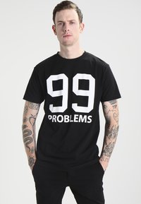 Must mustab lähedus, millel on tugeva valge tekstiga: "99 PROBLEMS", mis on selgelt rinnal. Õhuline sobivus, ümar kaelus.