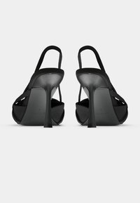 Čierne sandále s otvorenou špičkou a elegantným dizajnom, vybavené vysokým ihlovým podpätkom a nastaviteľným remienkom. Hladký povrch s minimálnymi ozdobami.