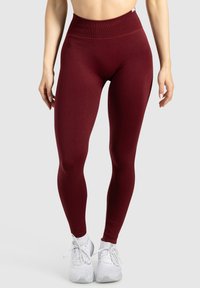 Leggings a vita alta e aderenti in un profondo bordeaux, realizzati in un tessuto liscio e elasticizzato, con una cintura larga e senza motivi visibili.