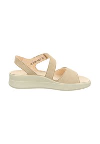 Beige Wildledersandalen mit Keilabsatz, die Kreuzgurte und eine niedrige, strukturierte Sohle aufweisen. Offene Zehenpartie mit gepolstertem Fußbett für zusätzlichen Komfort.