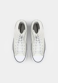 Hvit høyhælte sneakers med flate hvite lisser, gummitåhette og svarte detaljer. Glatt lærutside og merket innersåle.