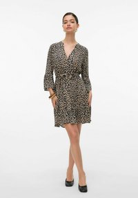 Robe en imprimé léopard dans des tons de beige et de noir, avec un design enveloppant, des manches évasées et une taille cintrée, se terminant au-dessus du genou.