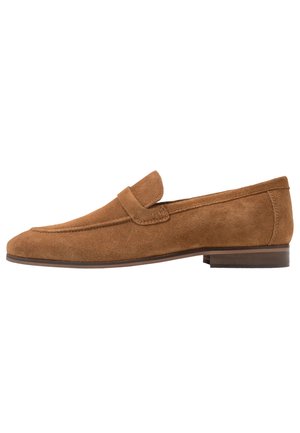 Brun ruskindslæder loafer med lav hæl og slip-on design, med en klassisk remdetalje over overdelen.