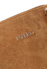 Brązowa torebka z zamszu o gładkiej fakturze, z elementami ze srebrnego metalu oraz z nazwą marki "RYŁKO" wytłoczoną w metalicznym kroju.