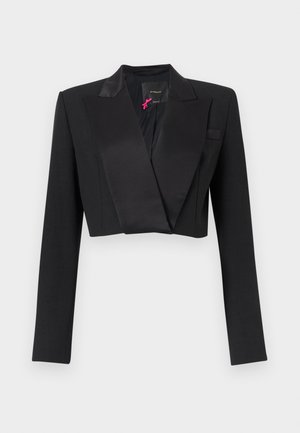 Veste courte noire avec larges revers en satin et manches longues, présentée sur un fond gris clair uni.