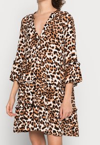 Abito a stampa leopardo realizzato in tessuto morbido, con scollatura a V, balze a strati e maniche a campana in tonalità di marrone e crema.