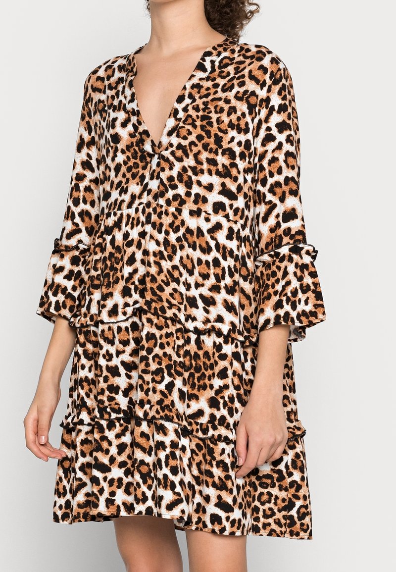 Abito a stampa leopardo realizzato in tessuto morbido, con scollatura a V, balze a strati e maniche a campana in tonalità di marrone e crema.