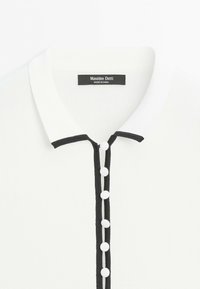 Wit overhemd met zwarte bies langs de knopenlijn en kraag, met zes witte knopen en een Massimo Dutti label binnenin de kraag.