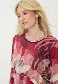 Top met lange mouwen in rood- en roze tinten, met abstracte patronen en een geribde halslijn met een mix van texturen en prints.