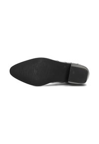 Zapato de cuero negro con punta afilada y suela texturizada, con un tacón bajo y detalles de costura decorativa a lo largo de los lados.