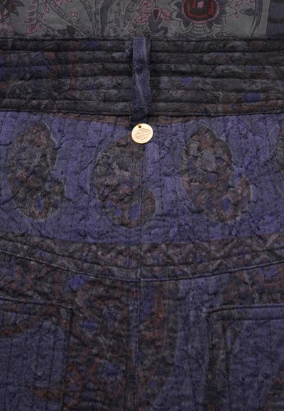 Kék mintás szövet texturált felülettel, redőzött derékpánttal és egy középen elhelyezett, fém díszgombbal, amely egy zseb fölött található.