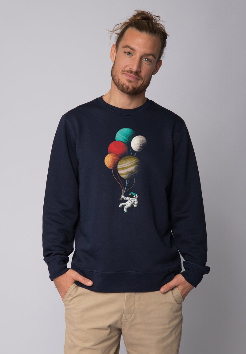 Sweat-shirt bleu marine présentant un astronaute tenant des ballons en forme de planètes colorées, conçu avec des textures et motifs vifs.