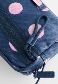 Jūras spēku auduma soma ar rozā punktiņiem, piemītot teksturētai virsmai, melna rāvējslēdzējs ar zigzaga šuvēm un bizītes rāvējslēdzēja vilkšana.