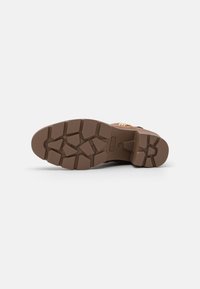 Sole in gomma marrone con un motivo a battistrada robusto, progettata per una buona trazione, con una finitura liscia e un branding ridotto.