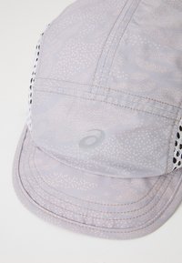 Casquette gris clair avec un motif à petits points subtil, côtés en maille et visière incurvée. Présente un petit logo argenté à l'avant.
