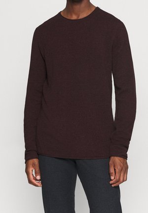 Sweater en tricot bordeaux à manches longues et col rond. La texture est légèrement côtelée, avec des manches ajustées et une coupe décontractée.