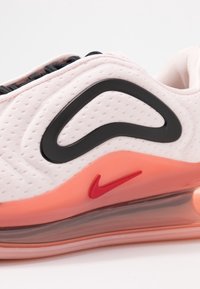 Sneakers Nike z różową siateczkową cholewką, czarnymi akcentami, dużym czarnym plastikowym logo Swoosh oraz przezroczystą podeszwą z poduszką powietrzną z czerwonym logo.