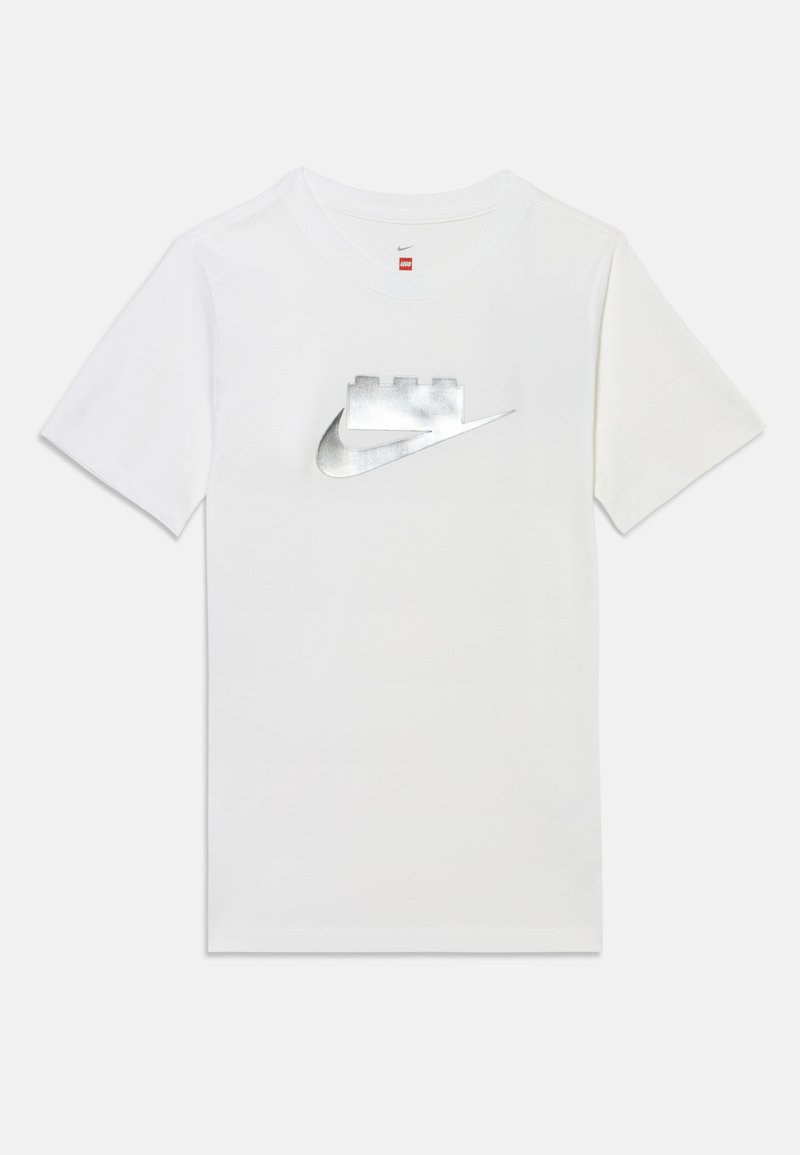 Λευκό T-shirt με κοντό μανίκι, ασημί λογότυπο Nike και σχέδιο τουβλακίων LEGO στο στήθος, μονόχρωμο φόντο.