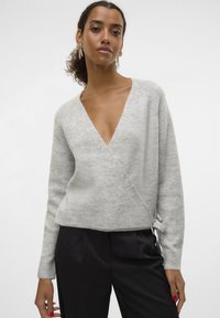 Light grey wrap sweater with a deep V-neck, long sleeves, and a textured knit. It features a tie detail at the waist.