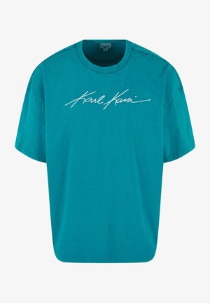 Tirkizna pamučna majica s ležernim krojem, okruglim izrezom, kratkim rukavima, i bijelim izvezenim potpisom "Karl Kani" sprijeda.