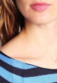 Sininen ja musta raidallinen neulepusero, leveällä pä�äntiellä, pehmeällä tekstuurilla ja näkyvillä saumaustiedoilla. Iho sävyt ovat luonnolliset ja sileät.