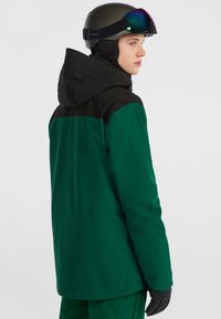 Grøn og sort isoleret skijakke, hætte design, glat tekstur, har en høj krave, synlige syninger og sorte accentpaneler.