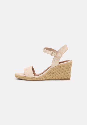 Wedge-sandaal met een textuur van bewerkt beige nepleer, enkelband met gesp en een geweven juten middenzool. Open teen ontwerp.
