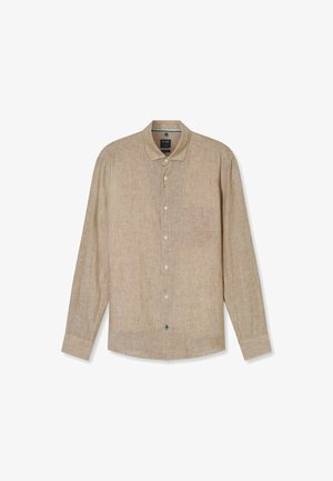 Chemise beige à manches longues en tissu texturé. Elle présente un col évasé, une fermeture boutonnée et une poche poitrine.