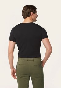 Black short-sleeve t-shirt with a rounded neckline, paired with olive green pants featuring two back pockets and a smooth texture.