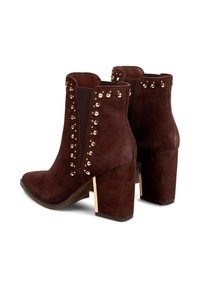 Botas de tobillo de ante marrón con adornos de tachuelas doradas, puntera afilada y tacón cuadrado. Presenta paneles laterales elásticos para un fácil uso.
