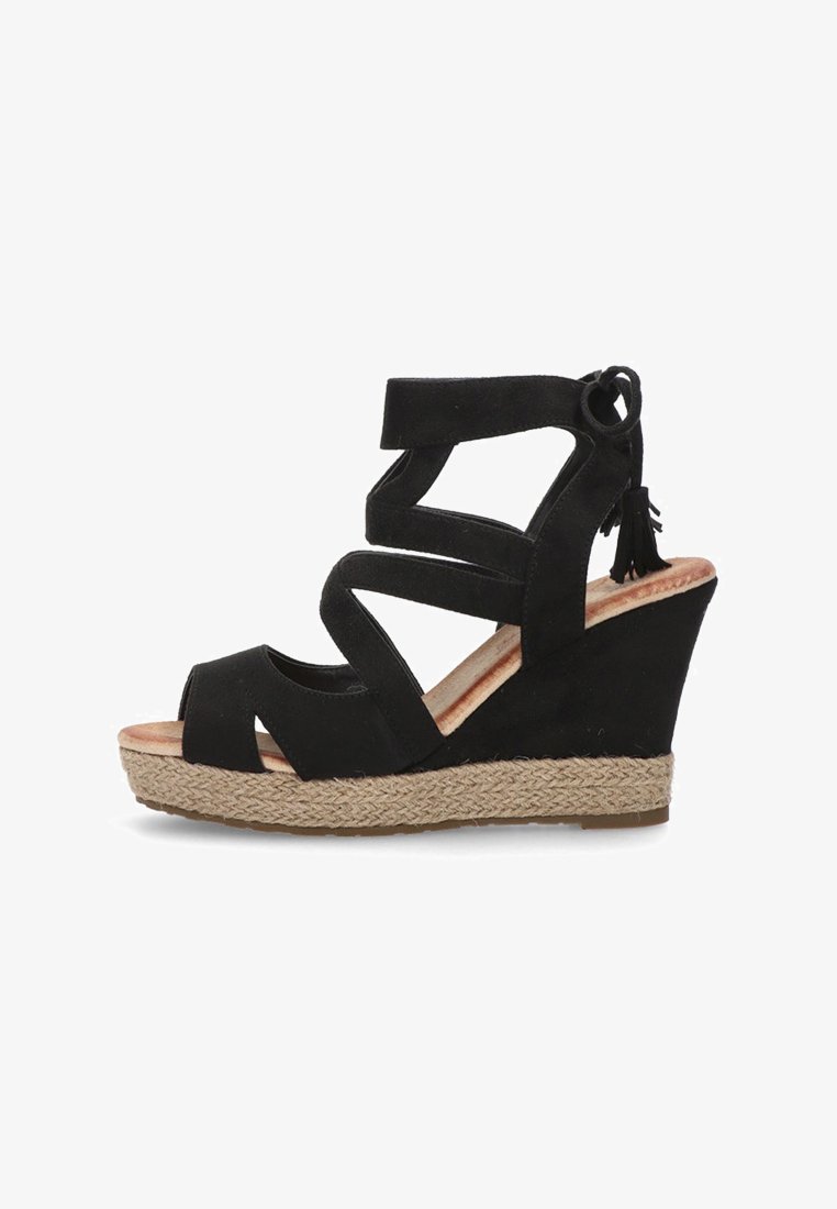 Sandalias de cuña de ante negro con múltiples tiras entrelazadas, punta abierta y borlas decorativas en el tobillo. Base tipo cuerda.