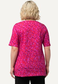 Camiseta de pulóver rosa con mangas cortas, que presenta un patrón texturizado de flores en varias tonalidades de rosa y púrpura.