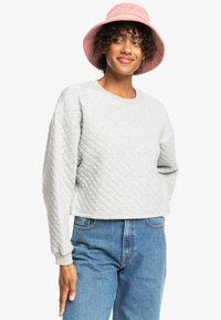 Gray quilted sweatshirt with a rounded neckline and ribbed cuffs, paired with light blue high-waisted jeans and a pink corduroy bucket hat.