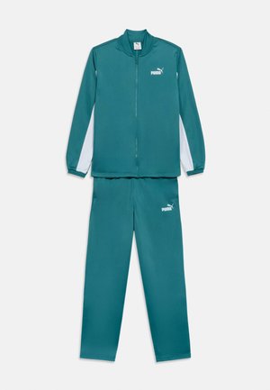 Türkizkék Puma melegítő fehér oldalsávokkal az ujjain, cipzáras, rugalmas mandzsettákkal és hozzá illő nadrággal, fehér háttéren kiterítve.