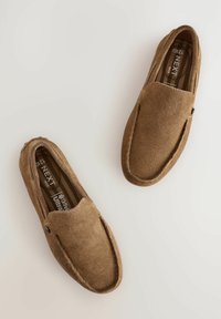 Braune Wildleder-Slipper mit abgerundeter Zehenpartie und sichtbaren Nähten, ausgestattet mit einer strukturierten Oberfläche und einer gebrandeten Innensohle.