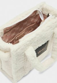 Borsa in pile bianco con manici corti, chiusura con zip e interno in raso con motivo a logo. Accento in pelle nera con logo sul lato.