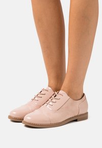 Scarpe in pelle rosa con lacci, caratterizzate da una punta in vernice e dettagli in suede, con una forma arrotondata e suola bassa.