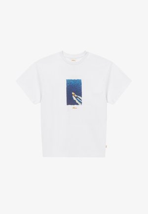 T-shirt blanc avec un graphique central représentant un bateau filant à toute vitesse à travers l'eau bleue de l'océan, créant un sillage blanc derrière lui.